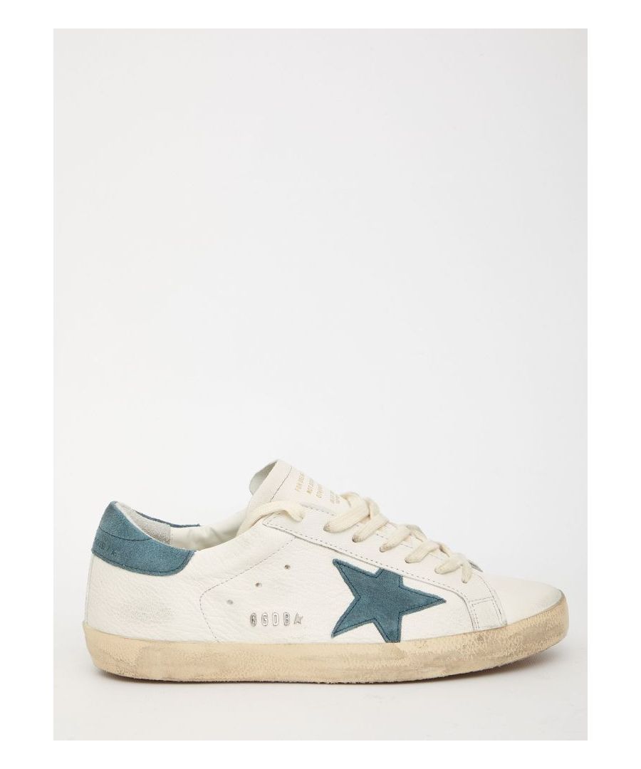 Super-Star sneakers in white leather with green suede side star and heel. They feature lace-up closure, Golden Goose logo on heel, metal GGDB lettering on the side, round toe and vintage effect.