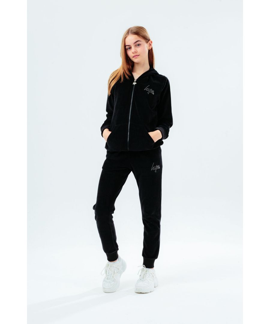 The HYPE. black velour diamante logo kids tracksuit set is the perfect loungewear choice when you need a lil extra comfort and style. In a velour fabric base for supreme comfort in our standard unisex kids jogger shape, highlighting an elasticated waist, cuffs and pockets. Featuring a fixed hood, pouch pocket and fitted cuffs. Finished with the iconic HYPE. script logo in diamante stones.