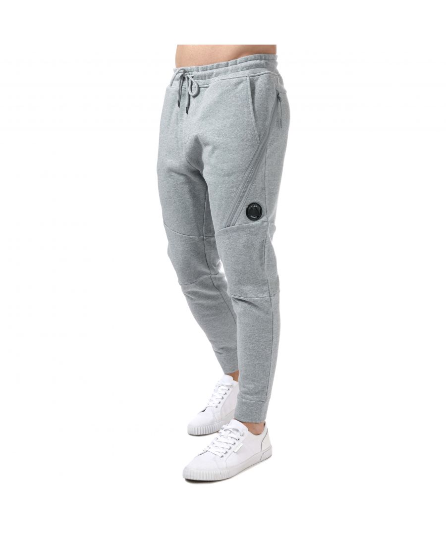 Mens C.P. Company Diagonal Raised Fleece Jog Pants in grey.- Elasticated waistband with an additional woven drawstring fastening.- Two pockets on the hips.- Additional cargo style pouch pocket on the thighs.- Single signature CP Company goggle on top.- Ribbed cuffs at the ankles.- Top stitching on the seams.- Main material: 100% Cotton. Machine washable.- Ref: 12CMSP084AM93A