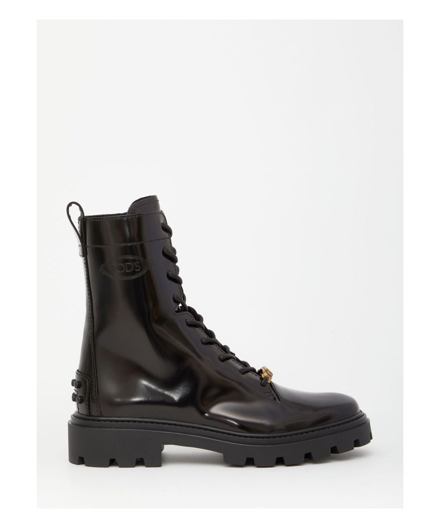 Laced boots in black brushed leather with gold metal logo tag on the front and visible stitching. They feature side zip closure, Tod's logo embossed on the side, rubber pebble detailing on the heel and lugged rubber outsole.