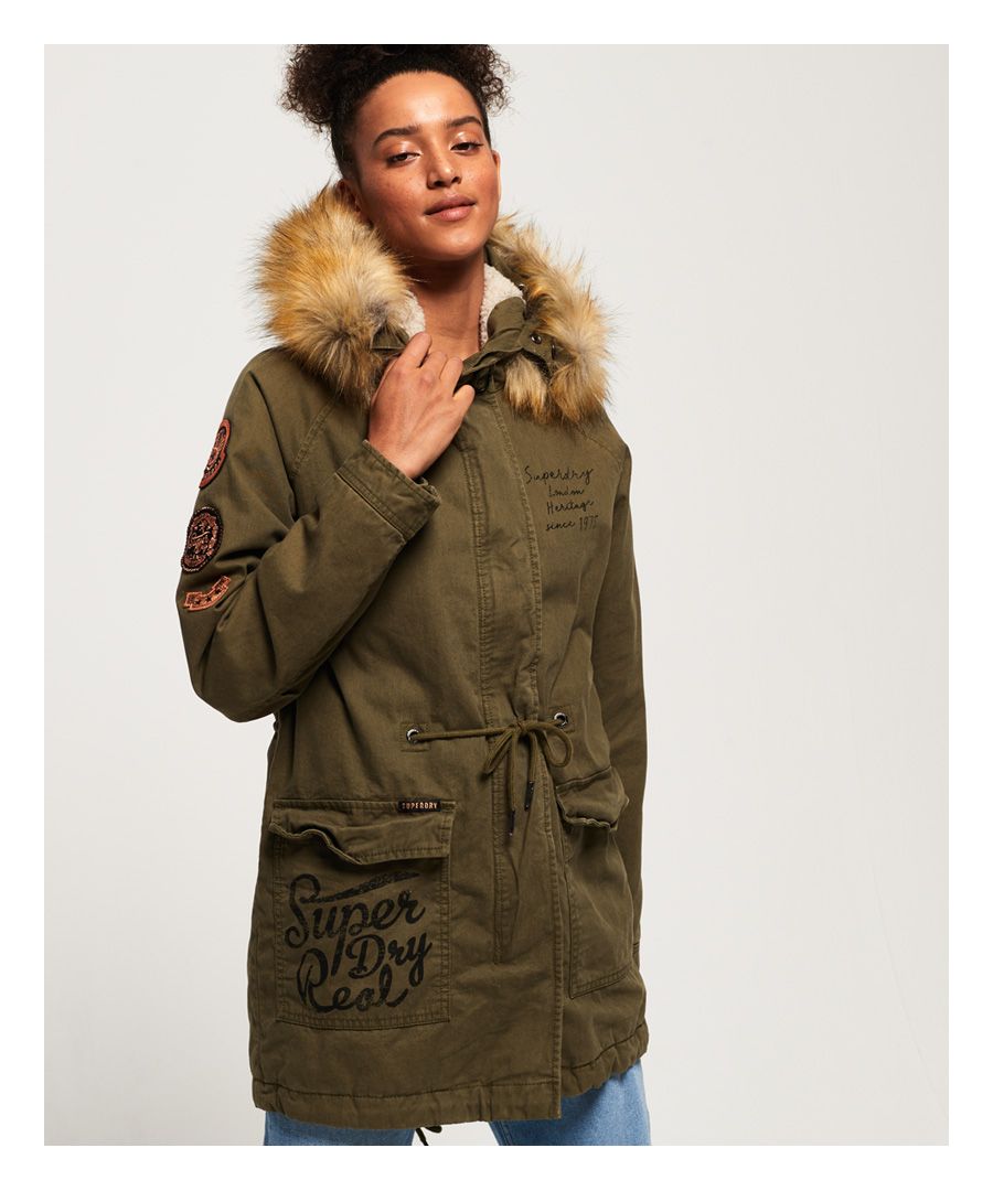 Superdry women's Rookie Heavy Weather tiger parka jacket. The perfect addition to your wardrobe this season, featuring a hood with a removable faux fur trim, a zip and popper fastening, popper fastened cuffs and two front pockets. The Rookie Heavy Weather tiger parka also features a warm fleece lining in the body and hood, a fishtail design and a drawstring adjustable waist for the perfect fit. This jacket is finished with a selection of military inspired badges on the sleeves and Superdry logos on the chest and pocket. Style this jacket with a pair of our skinny jeans and boots for a casual look.
