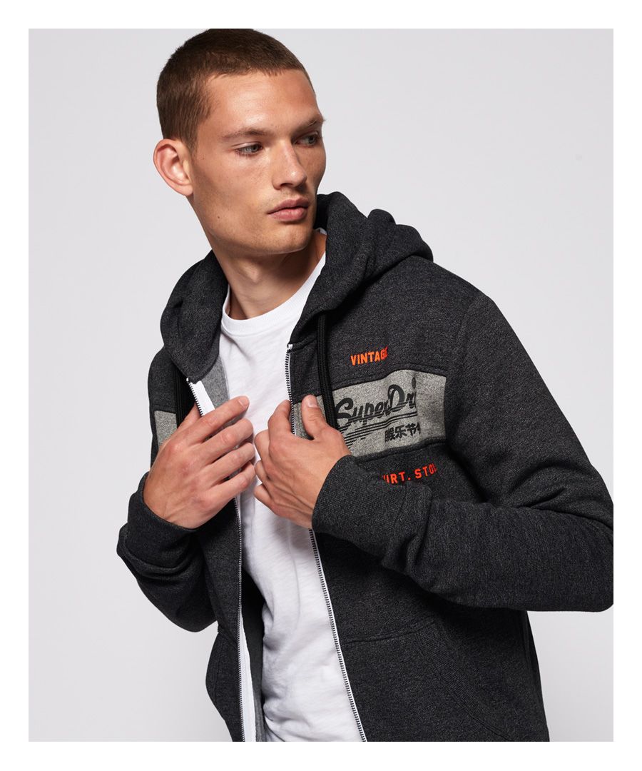 Superdry men's Sweat Shirt Shop Magma Panel zip hoodie. This hoodie features a full zip fastening, drawstring hood and front pouch pockets and ribbed cuffs and hem. Finished with a textured Superdry graphic on the front. Pair with jeans and a crew neck tee for casual styling.Slim fit