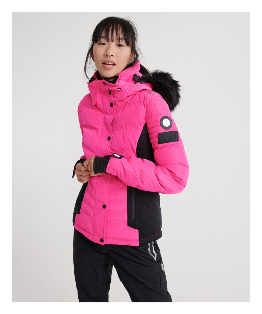 Superdry women’s Luxe snow puffer jacket. Designed for the slopes, this ski jacket features a detachable hood and faux fur trim as well as bungee cord adjusters. This snow jacket benefits from a total of three external zip pockets, including one on the left sleeve, and an internal pocket. This jacket also has earphone cable routing, a super soft lining and thumbholes on the cuffs as well as a hook and loop fastening, a popper snow skirt and a bungee cord fastening on the hem. This ski jacket is finished off with Superdry branding on the arm, shoulder and two Superdry logo badges on the sleeve.Waterproof rating <10,000mmWindproof rating <10,000g