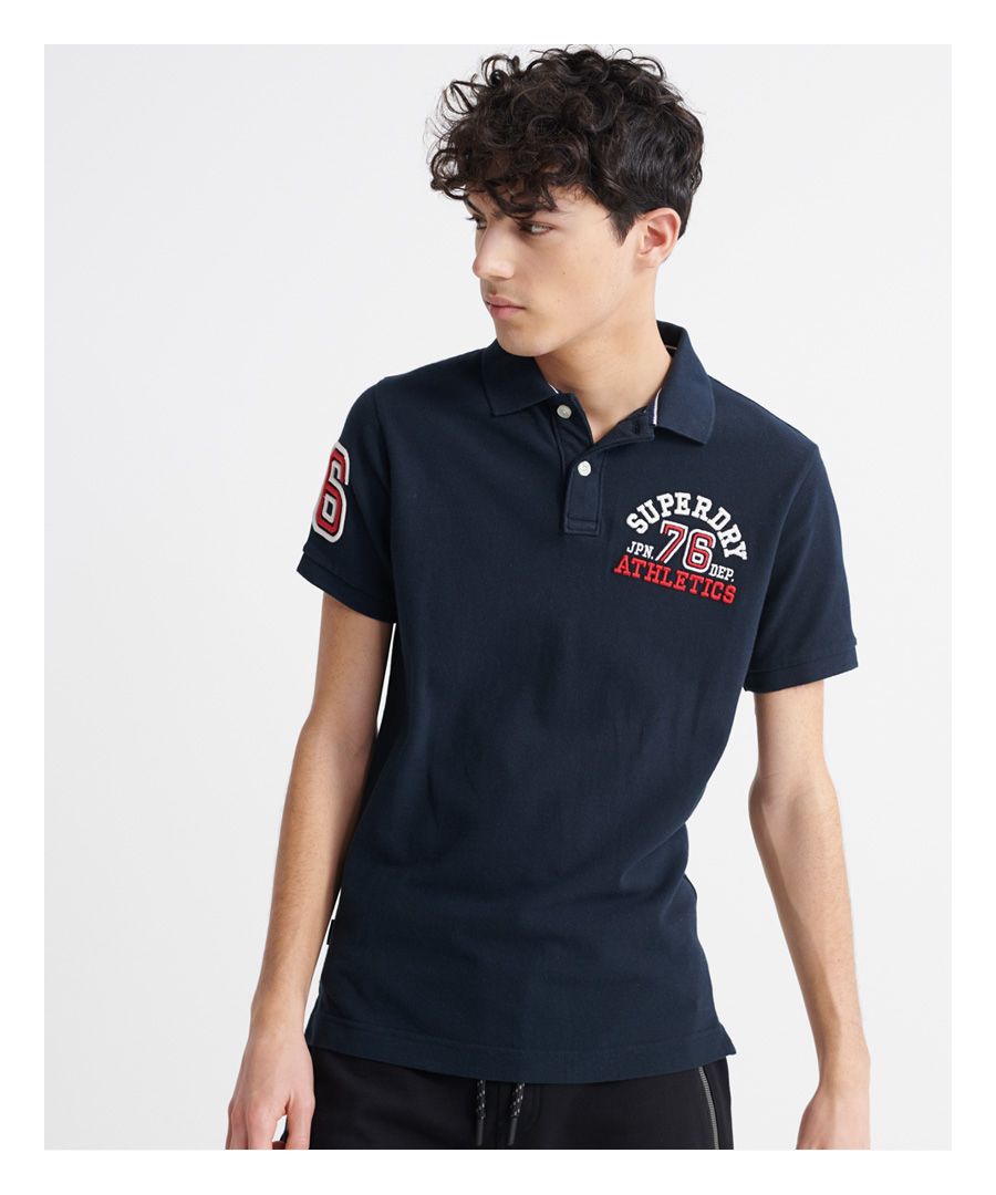 Superdry men's Classic superstate polo shirt. A staple in any wardrobe, this short sleeved polo features a button fastening at the collar, side splits at the hem, and a longer hem at the back. Finished with an embroidered number on one sleeve, and an embroidered Superdry logo on the chest.Made with Organic Cotton - Grown using only organic inputs and no artificial chemicals, which leads to improved soil condition, stronger biodiversity and better health among the cotton growers and uses between 60-90% less water to grow. By 2030, all Superdry Cotton will be Organic.Slim fit