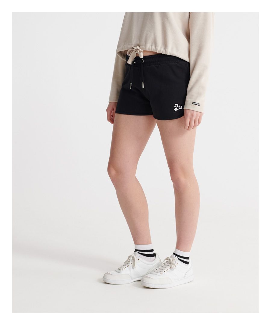Superdry women's Alchemy runner shorts. These shorts features a drawstring elasticated waistband, ribbed panel detailing on both sides and a textured Superdry graphic on one leg. Finished with a metal Superdry logo badge on the back of the waist.